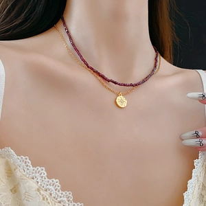 Gros plan d'un collier double rang avec perles et pendentif boussole sur le cou