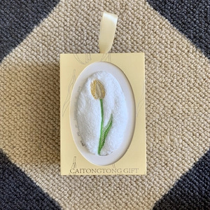 Detail of white coral fleece towel with tulip embroidery in a yellow gift box