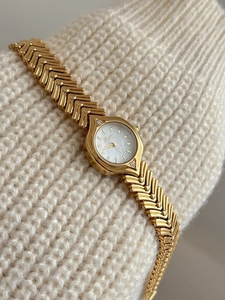 Detail of vintage gold women's watch with V-link strap and mother-of-pearl dial face