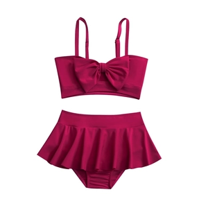 Two-piece girls swimsuit in rose pink featuring a large bow and pleated skirt bottom