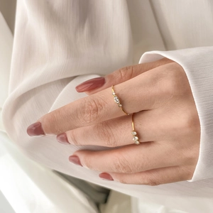 Detail of minimalist gold-plated rings with marquise and round zircon stones on hand