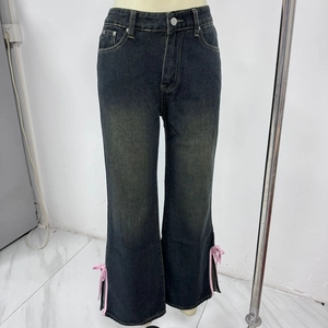 Détail de nœuds roses sur la fente latérale d'un jean évasé délavé foncé