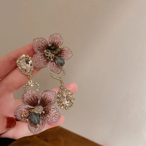Rosa Tulpenohrringe mit Tropfenkristallen und Silbernadeln in einer Hand gehalten