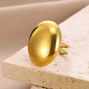 Macro shot of minimalist gold geometric dome ring on textured beige stone base