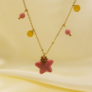 Detail of star-shaped pink stone pendant on a gold stainless steel necklace chain