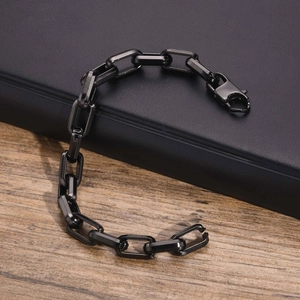 Detail of a black square link stainless steel bracelet with lobster clasp on leather