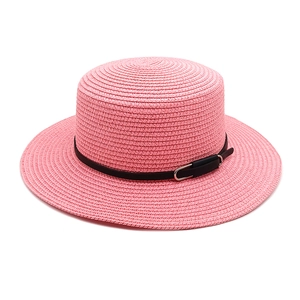 Détail d'un chapeau de paille rose avec une ceinture noire et une boucle argentée élégante