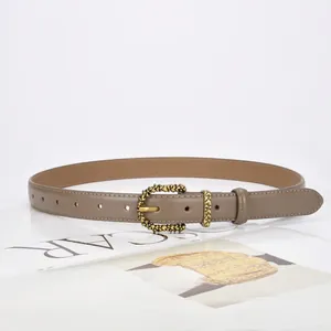 Minimalist taupe leather belt with an embossed vintage gold buckle on a white background