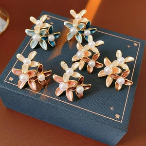 Detail of flower stud earrings with cat eye petals and pearl centers on a blue gift box