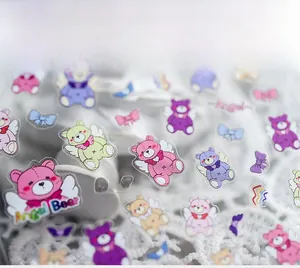 Macro shot of 3D glossy cartoon angel bear nail stickers with ribbon details on lace