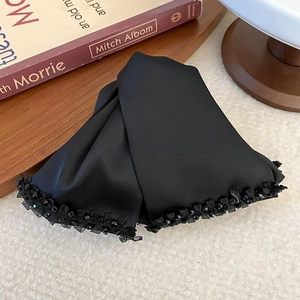 Elegant black satin bow hair claw clip with crystal bead trim on vintage book background