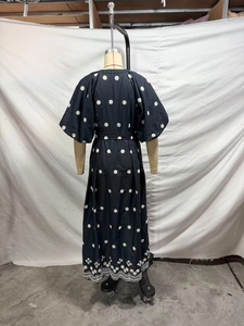 Detail of elegant black dress with white floral embroidery and scalloped lace hem on back view