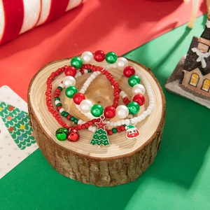 Close-up of Christmas beaded bracelets with Santa and tree charms on a rustic wood base