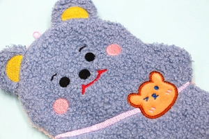 Detail of blue teddy fleece fabric and embroidered bear face on a cute pencil case
