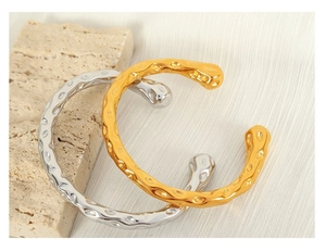 Detail shot of gold and silver open bangles with unique hammered texture on stone