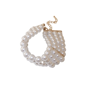 Bracelet élégant à quatre rangées de perles blanches avec chaîne dorée sur fond blanc neutre