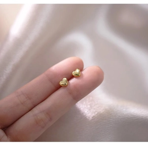 Close-up of mini gold heart-shaped S925 sterling silver studs shown for size scale