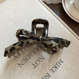 Detailed view of leopard print bow hair claw clip with shell texture and metal spring