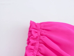 Détail du chemisier en mousseline rose montrant l'épaule plissée et la texture volantée