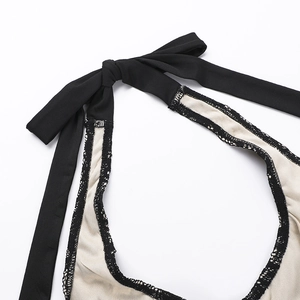 Détail de la bordure en dentelle noire et de la sangle licou sur un haut d'été beige