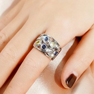 Vue détaillée d'une bague large ajourée avec pierres bleues et jaunes portée