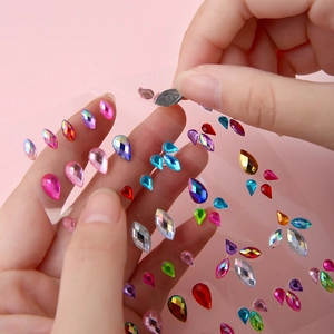 Self-adhesive colorful facial rhinestones and pearls on a sheet for stage makeup and decor