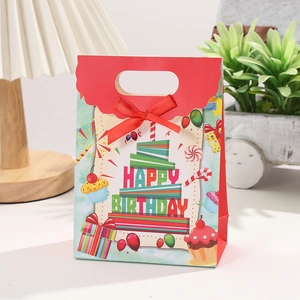 Detail of blue birthday gift bag with red ribbon bow and colorful cake printing
