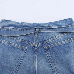 Détail d'un short en jean avec coutures orange classiques et poches arrière symétriques
