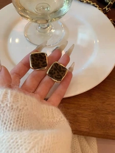 Detail shot of vintage leopard print square stud earrings with elegant gold trim edges