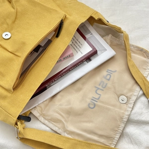 Interior view of yellow canvas crossbody bag showing spacious main compartment and lining
