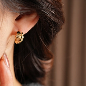 Close-up of 14K gold plated serpent hoop earrings with sparkling cubic zirconia on model