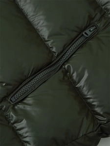 Detail of a dark green puffer jacket featuring glossy nylon fabric and matching resin zipper