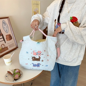 Close-up of light blue quilted tote bag featuring colorful cat embroidery and luck text
