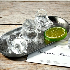 Macro detail of penguin-shaped ice cubes on a metal tray with fresh lime garnish