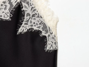 Detailed close-up of delicate eyelash lace trim on black satin fabric top for women