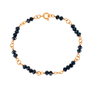 Detailed close-up of golden chain bracelet with dark blue faceted beads and spring clasp