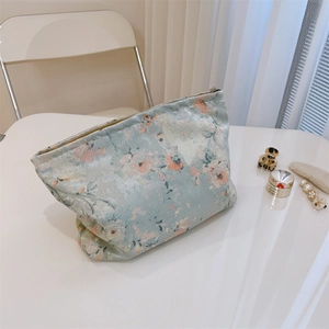 Detailed view of vintage floral jacquard makeup bag with metal zipper on a white desk