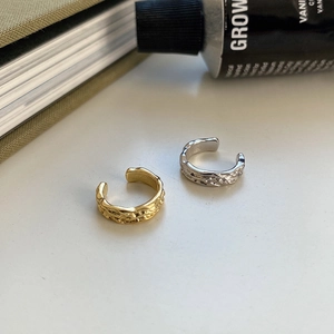 Pair of gold and silver irregular lava texture ear cuffs on a white surface