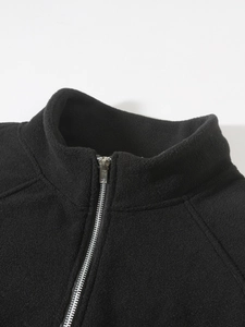 Close-up of black coral fleece fabric texture with durable silver metal zipper detail