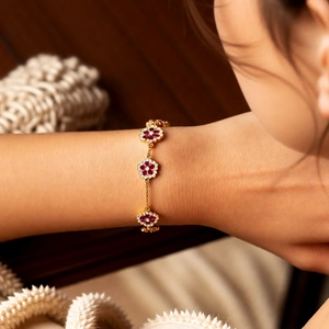 Close-up of 18k gold flower bracelet with red gems and diamonds on female wrist