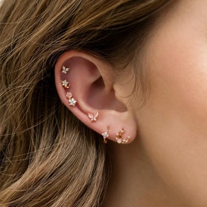 Star and moon ear piercing set with pink crystals in 18K gold plating on model's ear