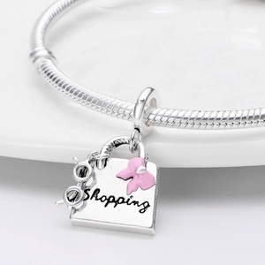 Silver snake chain bracelet featuring a shopping bag charm with a pink bow and black glasses