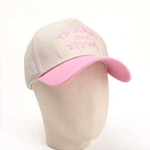 Close-up of pink 'TANNER and TIPSY' embroidery on an off-white cotton baseball cap