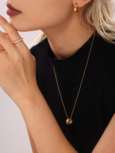 Detail of layered gold three-ring necklace and pavé rings on a model in black knitwear