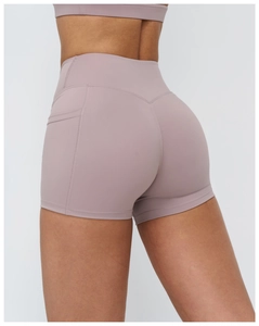 Detail view of high-waist yoga shorts in dusty rose featuring a V-shaped back seam and pocket