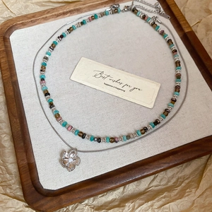 Close-up of double-layer beaded flower necklace on elegant wooden tray packaging