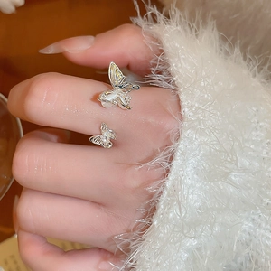 Close-up of elegant double butterfly open ring with zircon and white opal inlay