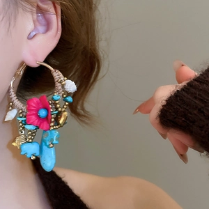 Detailed macro view of bohemian hoop earrings with pink cloth flowers and blue beads