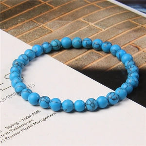 Detailed close-up of 6mm blue turquoise style beads bracelet on a lifestyle magazine