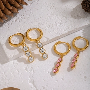 Gold hoop earrings with pink and white zircon charms on a textured white background